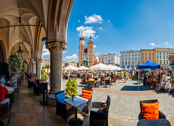 Main Market square of Krakow Krakow full of tourists having a coffee break under the archs of the Cloth Hall krakow stock pictures, royalty-free photos & images