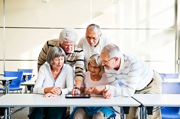 gruppo di anziani esaminare digital tablet - senior adult group therapy social gathering community center foto e immagini stock