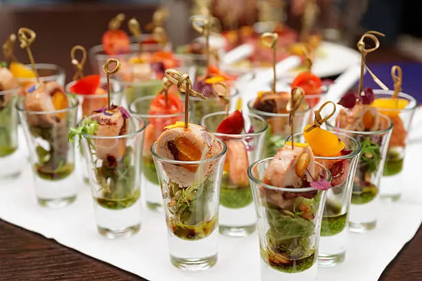 Various snacks in shot glasses on table