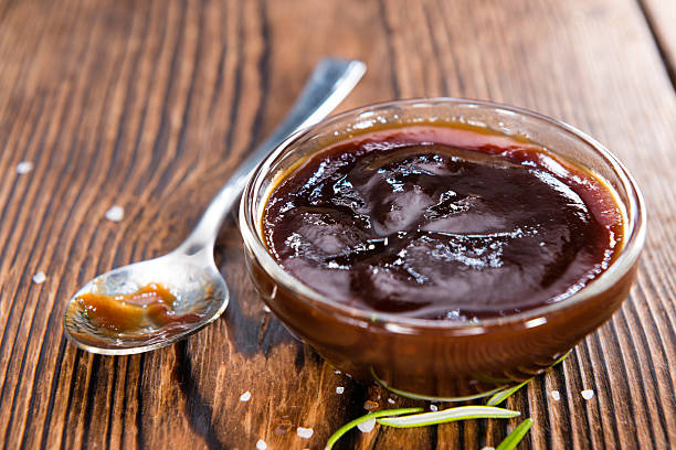 Barbeque Sauce Barbeque Sauce with Tomatoes, Smoked Salt and fresh Herbs (on rustic wooden background) savory sauce stock pictures, royalty-free photos & images