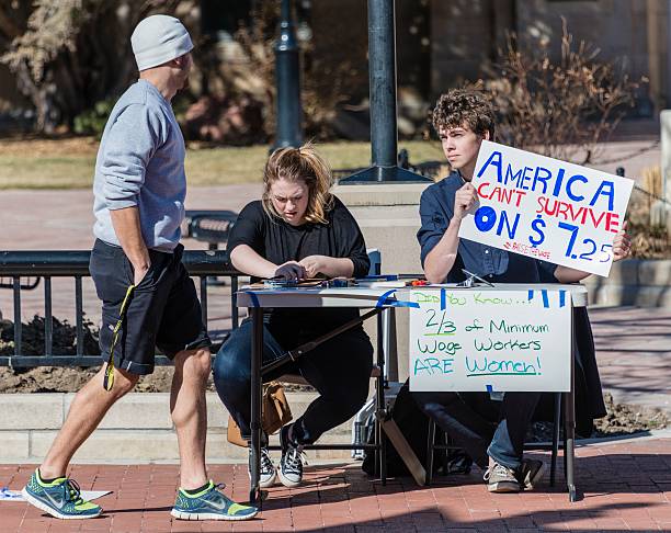 Raise the Minimum Wage Boulder, Colorado, USA - February 19, 2014: Two young people in downtown Boulder explain why Americans can't survive on $7.25 minimum wager per hour. minimum wage stock pictures, royalty-free photos & images