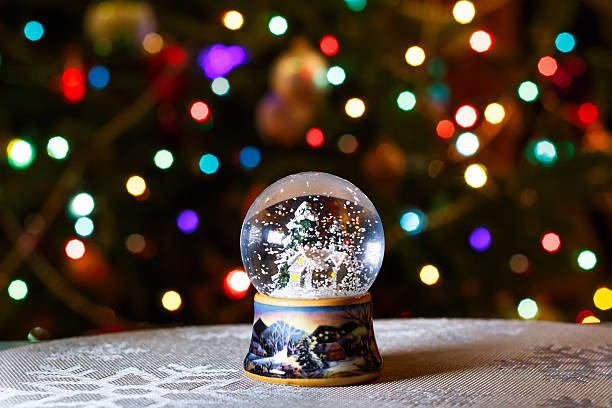 globo de neve de natal em frente de luzes árvore de natal grande - luminant imagens e fotografias de stock