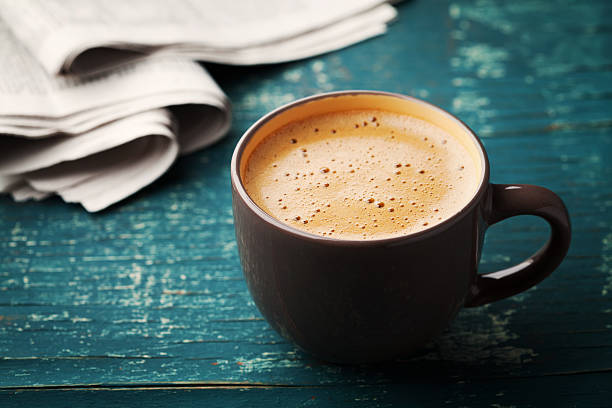 Coffee mug with newspaper on teal rustic table, cozy breakfast