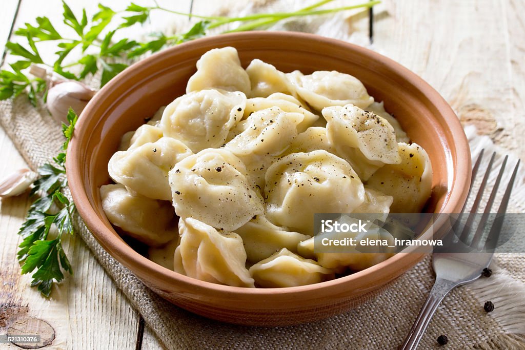 Dumplings with meat in the bowl on the table Dumplings with meat in the bowl on the table in a rustic style. Traditional Russian and Ukrainian cuisine. Bay Leaf Stock Photo