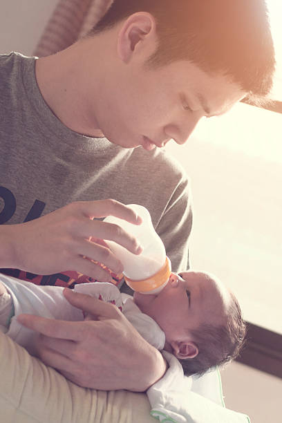 istock Young father feeding baby boy with milk bottle 521311410
