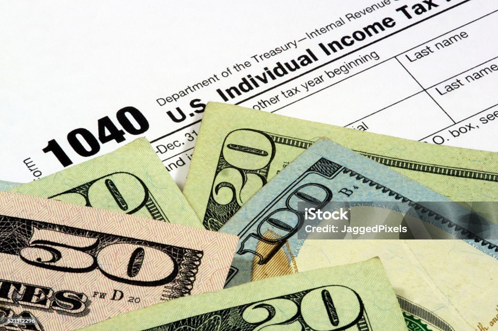 Tax Form and Currency A 1040 income tax form with United States currency. The corner of the Twenty Dollar bill obscures the year to add to the image usefulness. Internal Revenue Service Stock Photo