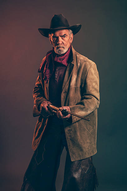 istock Senior cowboy with gray beard and brown hat holding rifle. 521315063