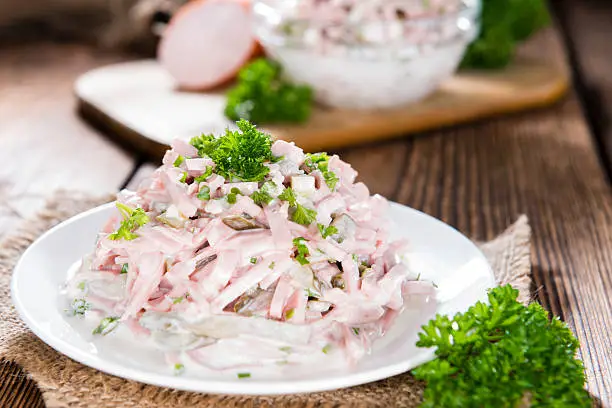 Meat Salad made with mayonnaise (close-up shot) on wooden background