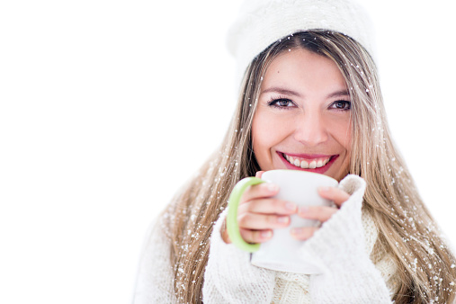 Winter woman drinking a cup of coffee - isolated over white