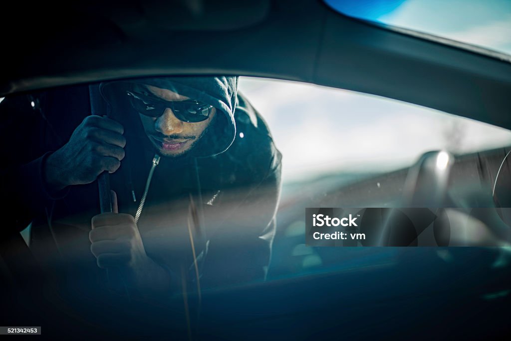 Car Thief Using a Tool to Break into Car Car thief stealing the car. Car Stock Photo