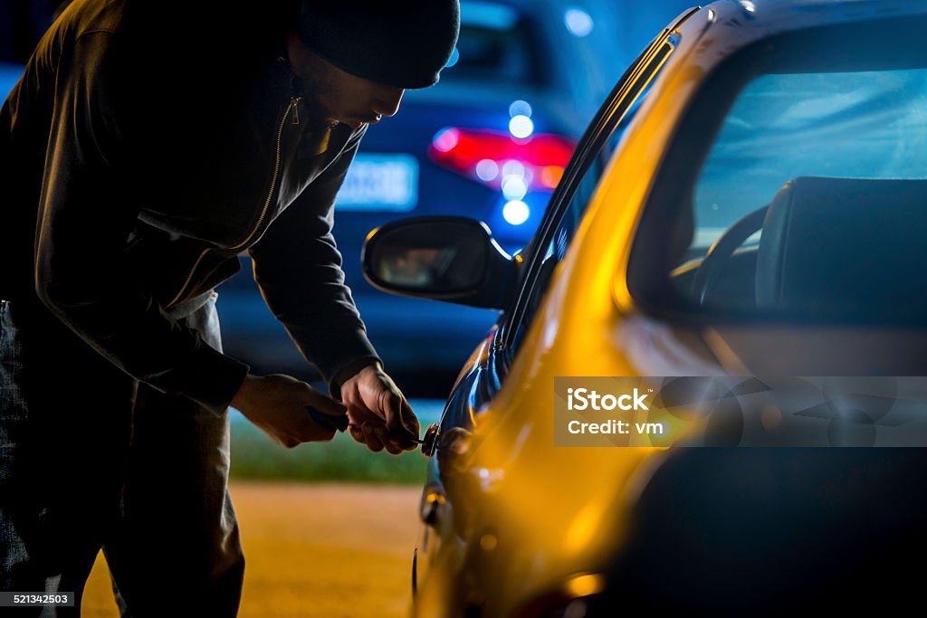 Car Thief Using a Screwdriver to Brake into a Car Car thief stealing a car. Stealing - Crime Stock Photo