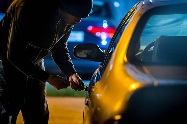 Car Thief Using a Screwdriver to Brake into a Car Car thief stealing a car. thief stock pictures, royalty-free photos & images