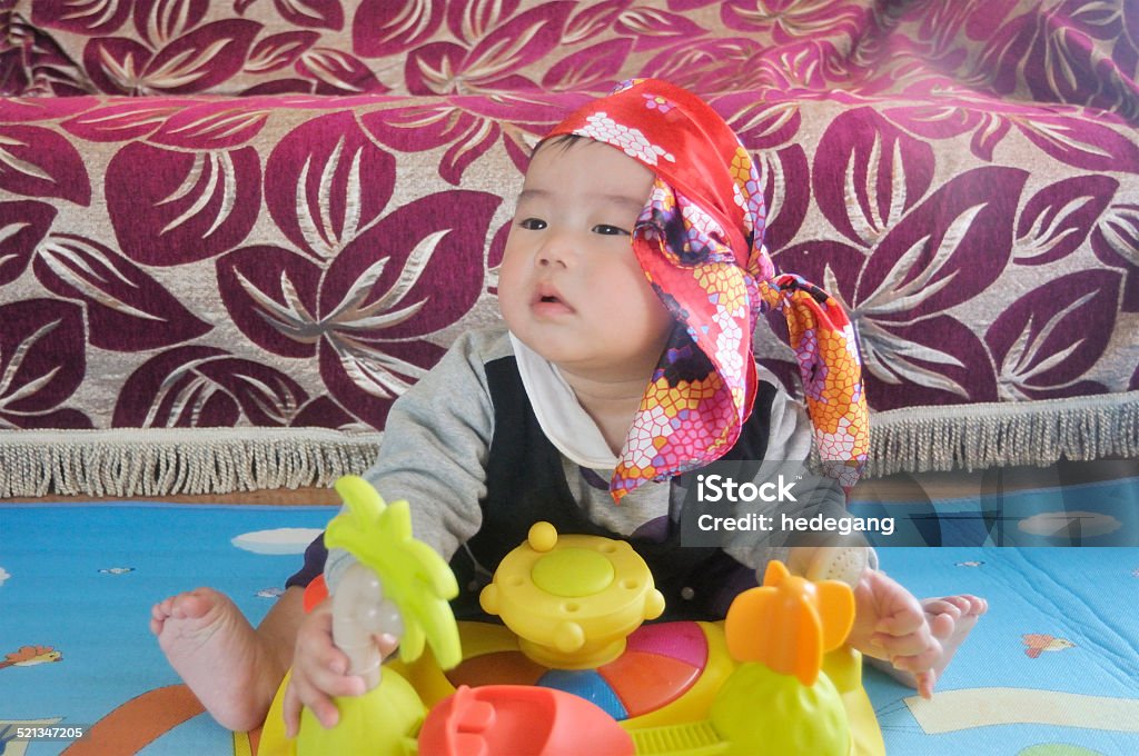 asian baby boy playing and thinking  in room Happy asian baby boy  with headscarf sitting on floor and playing with toy and thinking something. 6-11 Months Stock Photo