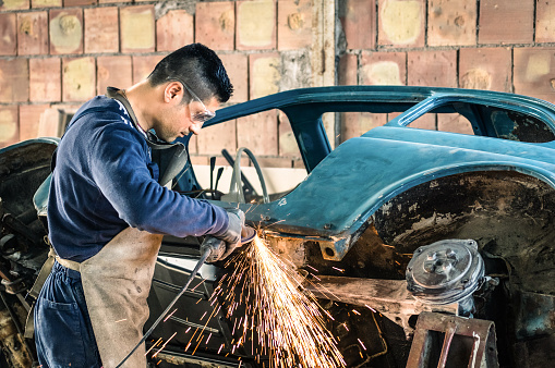 Joven trabajador mecánico arreglando un coche de época antigua photo