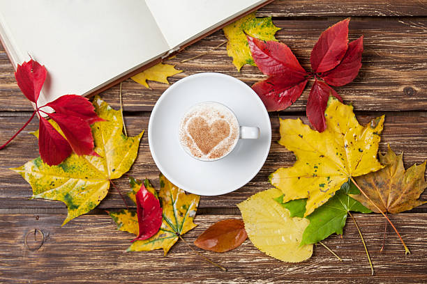 istock Autumn leafs, book and coffee cup on wooden table. 521364959