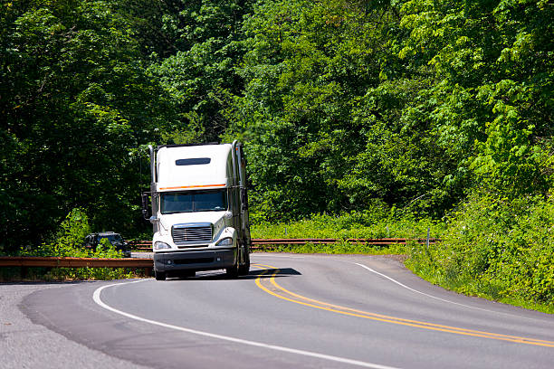 istock White semi truck winding green road 521367231