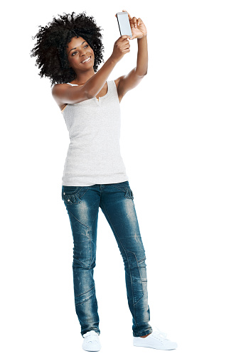 Studio shot of attractive african woman with afro taking a picture of herself with her camera phone