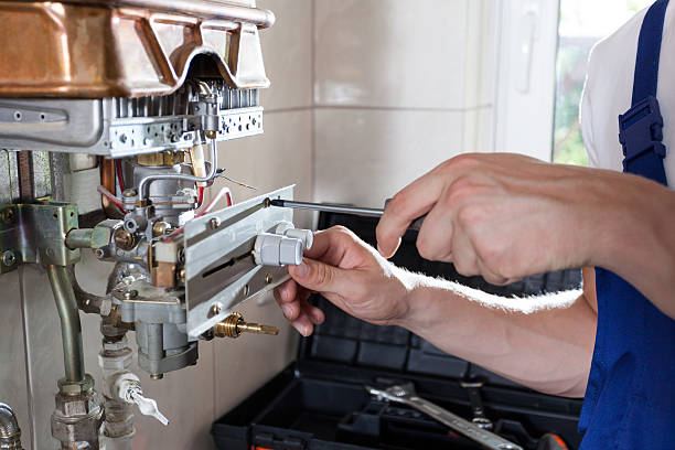 Handyman adjusting gas water heater Repairman fixing a gas water heater with a screwdriver adjustable wrench photos stock pictures, royalty-free photos & images
