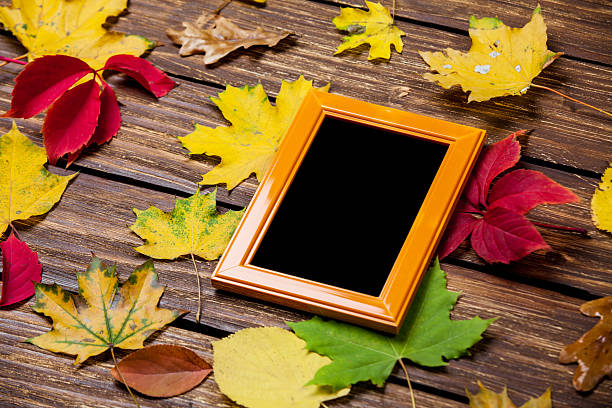 istock Autumn leafs and frame for photo on wooden table. 521368089
