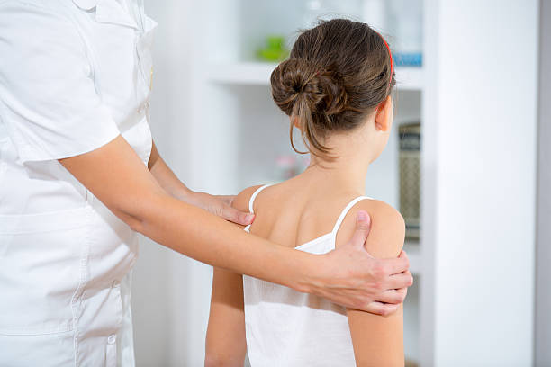 istock Chiropractic Doctor Adjusts Elementary Girl 521370673