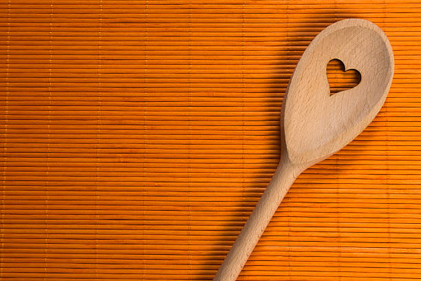 istock wooden spoon on orange background 521373020
