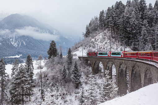 Famous sightseeing train running over viaduct in Switzerland, the Glacier Express in winter