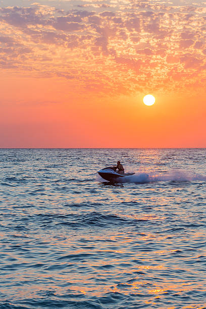 istock Man riding jet ski on colorful sunset 521377432