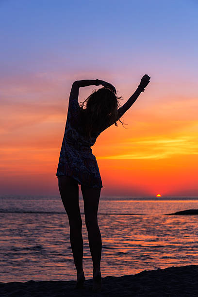 istock Beautiful young woman on the beach at sunset 521380558