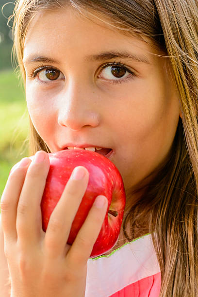 istock Seven year old girl biting a red apple 521383015