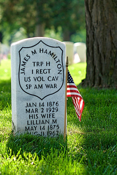 Tombstone, U.S. Flag, Spanish-American War, Arlington National Cemetery Arlington, Virginia, USA - May 24, 2015: Close-up of a small U.S. flag and tombstone honoring a Spanish-American War veteran and his wife at Arlington National Cemetery. arlington cemetery in spring stock pictures, royalty-free photos & images