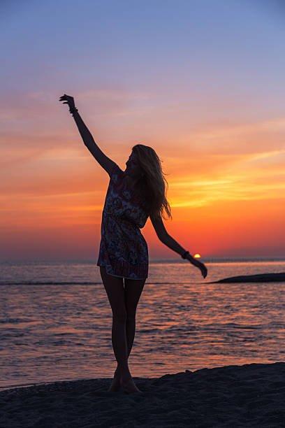 istock Beautiful young woman on the beach at sunset 521386540