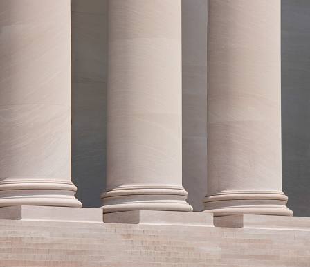 Three tall marble doric columns outside a courthouse.