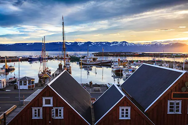 sunset at husavik bay in iceland where you can see a few sailships at dock