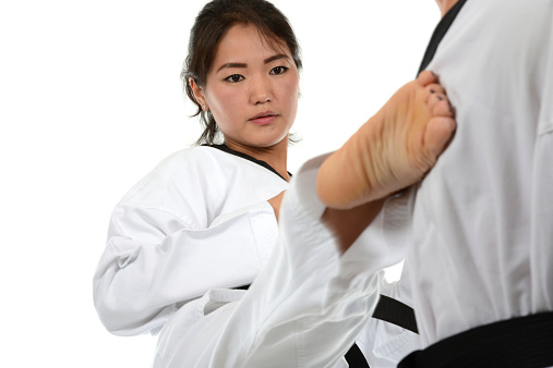 Mongolian woman Kicking the chest of a martial arts training manikin.