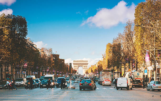 Traffic in Champs Elysees Street Traffic of cars and people along avenue de Champs-Elysẻes in autumn time, Paris, France. The Arc de Triomphe in the background. avenue des champs elysees photos stock pictures, royalty-free photos & images