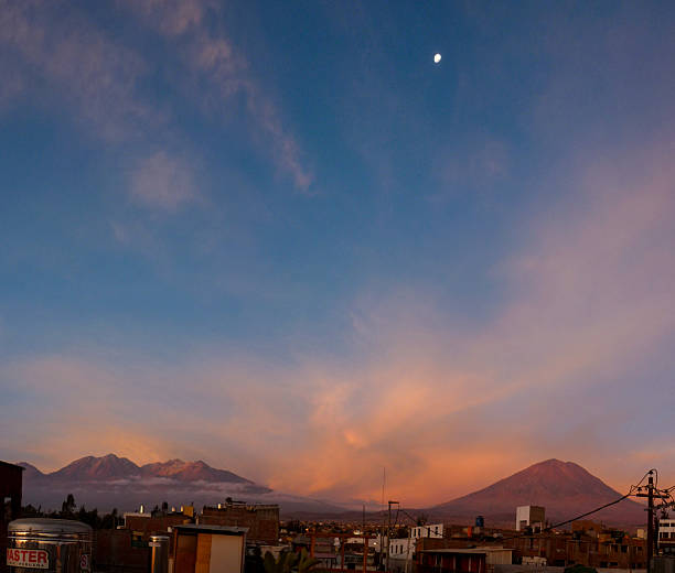 The moon shines bright over the mountain El Misti in the city if Arequipa, Peru during a very colorful sunset.