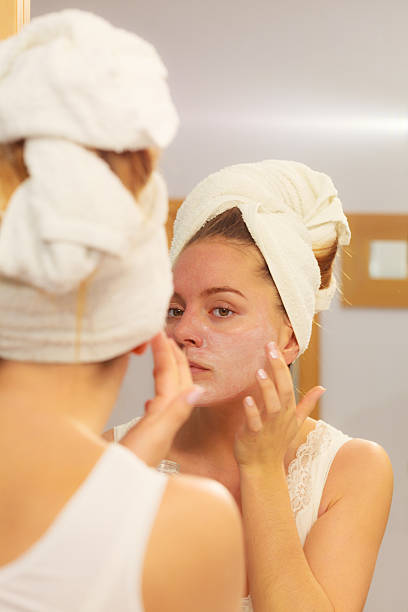 istock Woman applying mask cream on face in bathroom 521417110