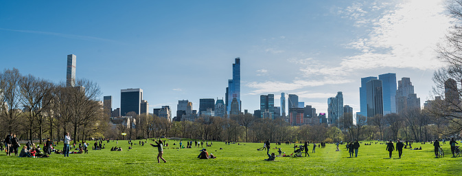 New York, USA - April 10, 2016: 10-April-2016- New York, NY- Tourists and locals enjoy spring weather on the Great Lawn in Manhattan, New YorkClose up of green grass blades with skyscrapers of NYC in background