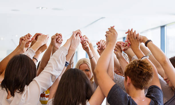 Group of women holding hands. Unity concept Group of women standing toghether in the circle and holding raised hands. Unity concept. unyielding stock pictures, royalty-free photos & images