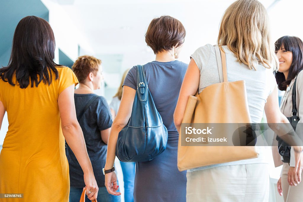 Group of women walking the hall, back view Back view of group of women walking down the hall and discussing. Crowd of People Stock Photo