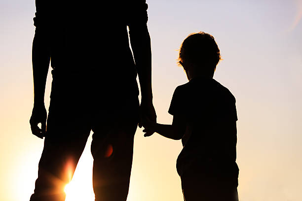 istock silhouette of father and son holding hands at sunset 521418748