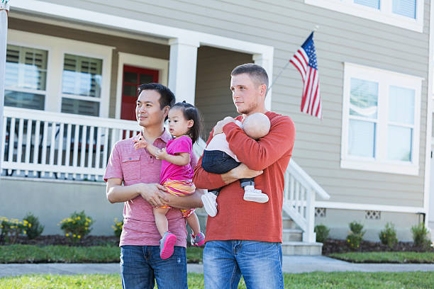 istock Two fathers holding young children standing outdoors 521418778