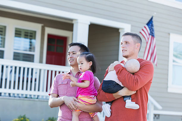 istock Two fathers holding young children standing outdoors 521419268