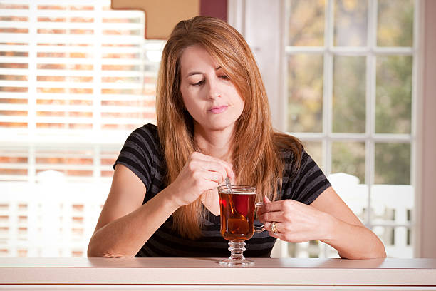 istock Melancholy Woman Looking Down As She Stirs Her Tea 521419269