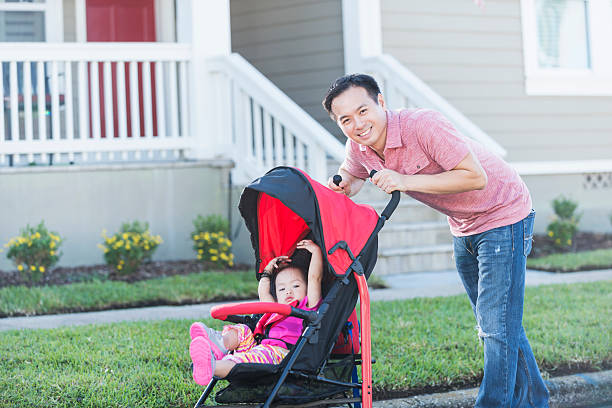 istock Asian father pushing his daughter in stroller 521419298