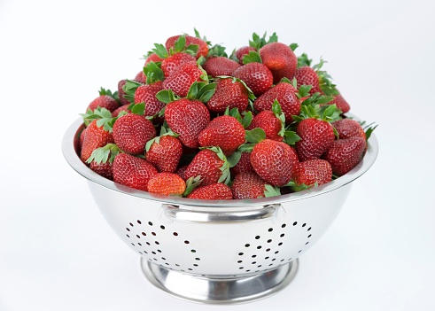 A colander of fresh from the field strawberries.