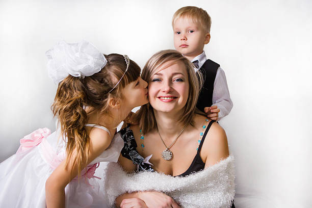 Two children kiss and embrace the gentle mother