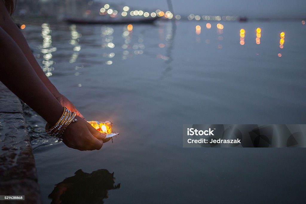 Varanasi_Puja_2 A evening shot of a woman putting blessed puja flowers in the river Ganges in Varanasi, India Ganges River Stock Photo