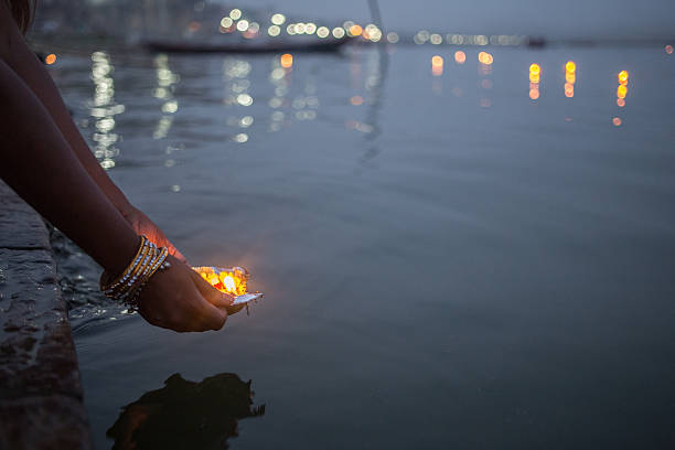 Varanasi_Puja_2 A evening shot of a woman putting blessed puja flowers in the river Ganges in Varanasi, India ceremony stock pictures, royalty-free photos & images