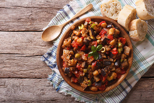 caponata mit auberginen in einer hölzernen platte. horizontale aufsicht - caper sauce stock-fotos und bilder